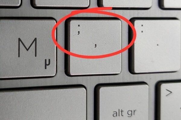 Silbergraue Notebooktastatur, die Taste mit Komma und Semikolon ist rot eingekreist