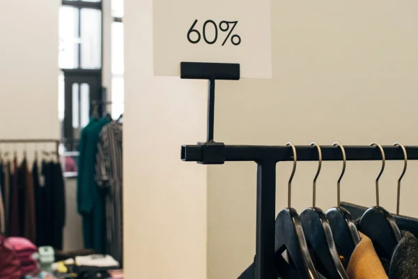 Vorteilhafte CTAs formulieren: Innenraum eines Ladengeschäfts mit mehreren Kleiderstangen, im Vordergrund eine Stange mit Jacken und der Aufschrift "60 %".